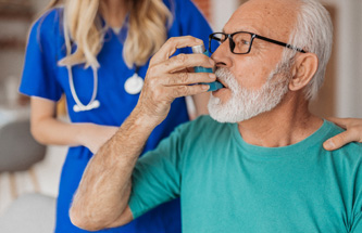 older man using an asthma inhaler